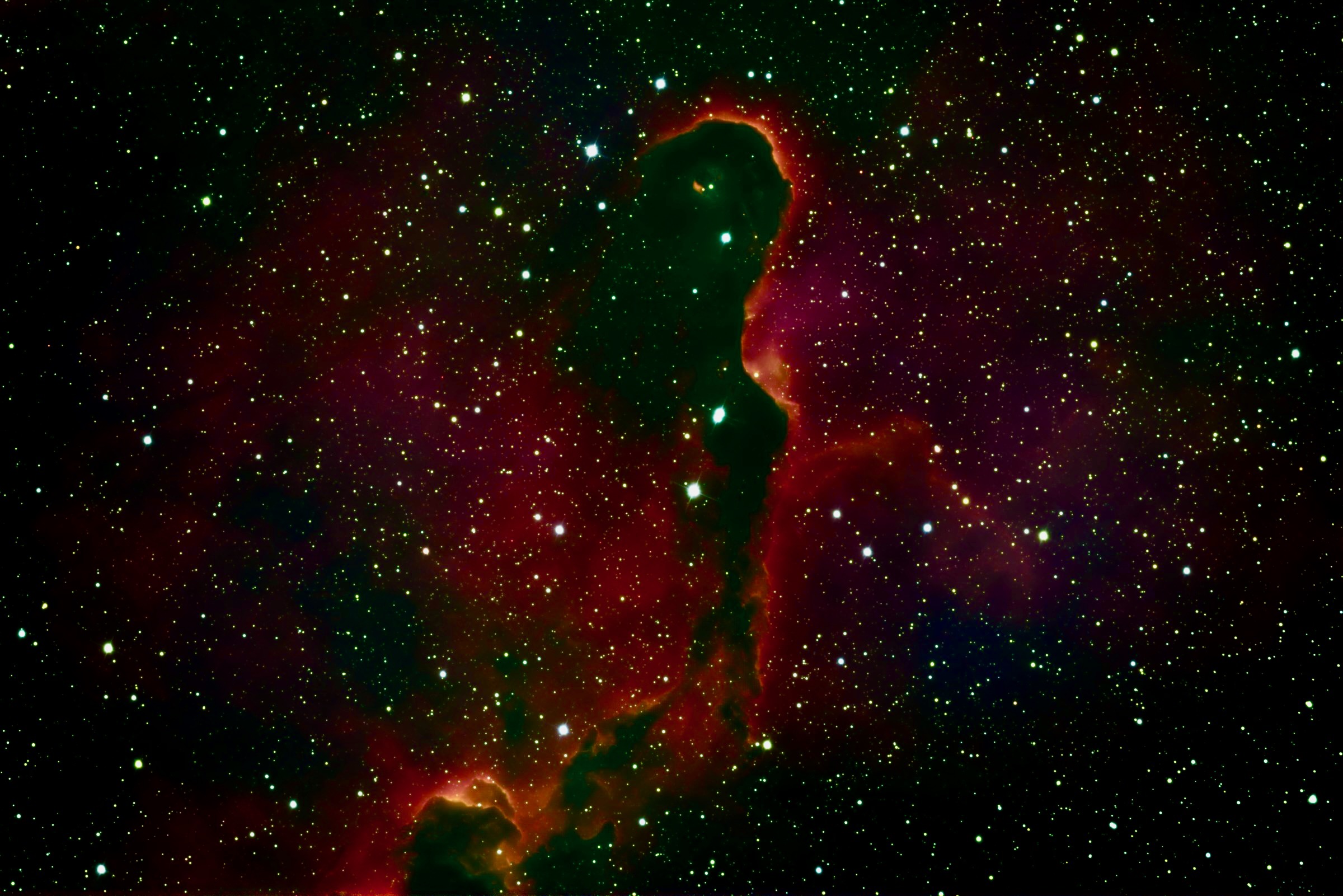 The Elephant's Trunk Nebula in the HSO palette: a dark winding column of dust silhouetted against a red and magenta field of glowing hydrogen, its edges rimmed in orange where the ionization front burns.